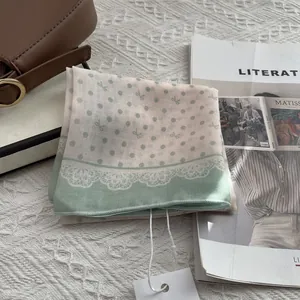 Detailed close-up of a light green polka dot cotton scarf folded on a magazine background