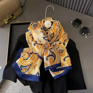 Macro detail of silk scarf with yellow and navy paisley pattern on black top