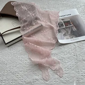 Détail de la broderie florale sur un foulard en dentelle rose avec texte Hope