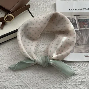 Close-up of cotton linen scarf featuring sage green polka dots and bow print textures