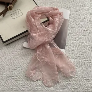 Detailed close-up of pink lace embroidery and delicate scalloped edges on the scarf