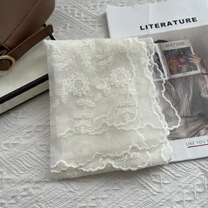 French lace scarf with sunflower embroidery and scalloped edges on white textured surface