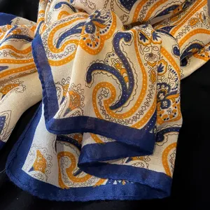 Detail of soft paisley scarf showing blue and orange patterns on woven silk fabric
