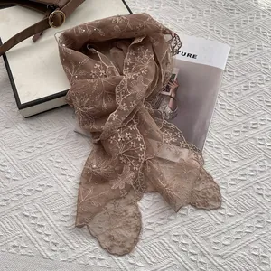 Macro shot of brown lace scarf with floral embroidery, pearls and rhinestones details