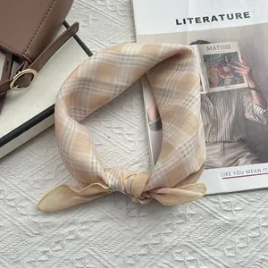 Dettaglio di un foulard di cotone a quadri annodato con eleganza su una borsa retrò