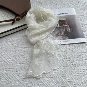 White sunflower lace scarf with floral embroidery and scalloped edges on white surface
