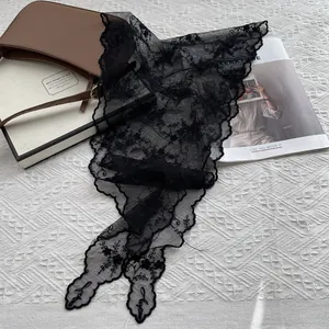 Détail d'un foulard en dentelle noire avec broderie florale et bords festonnés