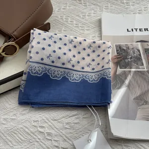 Detailed view of blue and white polka dot scarf with delicate white lace edge finish