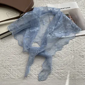 Détail de bandana en dentelle bleu clair avec broderie florale sur fond texturé