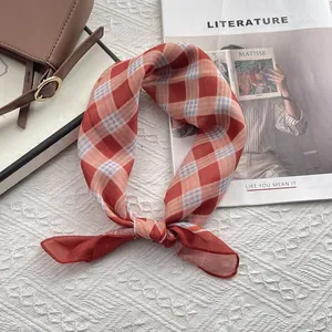 Dettaglio di un foulard a quadretti arancione su una borsa di pelle marrone con rivista