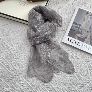 Close-up of grey lace scarf with white floral embroidery and delicate faux pearls