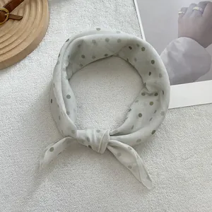Detailed view of a soft light grey polka dot scarf tied in a stylish ribbon knot