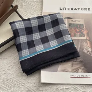Dettaglio di sciarpa in cotone a quadri blu navy su sfondo vintage e pizzo
