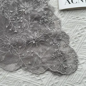 Macro shot of gray lace fabric with 3D butterfly floral embroidery and pearl details