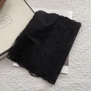 Detail shot of black lace scarf with delicate floral embroidery and scalloped edges