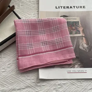 Dettaglio di sciarpa in cotone a quadri rosa con bordi overlock su sfondo di una rivista