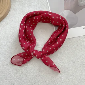 Detail view of red polka dot neck scarf with soft drape on a textured background