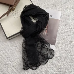 Detail of black lace scarf featuring floral embroidery and elegant scalloped edges