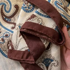 Detail shot of vintage paisley pattern scarf with beige base and dark brown border fabric