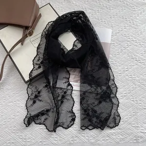 Detail of elegant black lace scarf with floral embroidery and scalloped edges