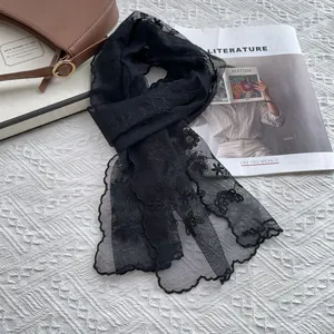 Close-up of elegant black lace scarf with delicate floral embroidery and scalloped edges