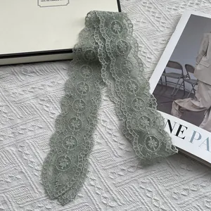 Detail of sage green lace scarf with floral embroidery and scalloped wavy edges