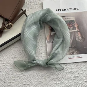 Dettaglio di un foulard di cotone a quadri verde chiaro su una borsa a mano elegante
