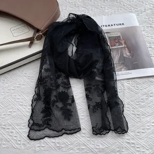 Detail of black lace scarf featuring floral embroidery and elegant wavy scalloped edges
