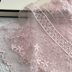 Detail eines hellrosa Spitzenschals mit feiner Stickerei und wellenförmigen Kanten