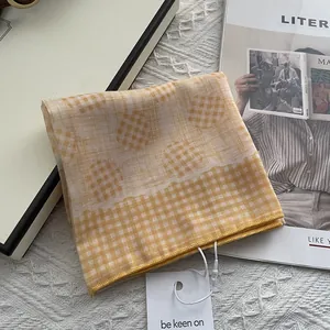 Yellow and white checkered 80s yarn square scarf with polka dots and brand tag on carpet