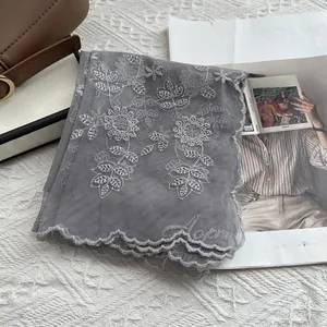 Close-up of grey lace scarf featuring sunflower embroidery and scalloped edges