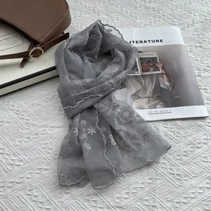 Detail of grey lace scarf featuring delicate sunflower embroidery and scalloped edges
