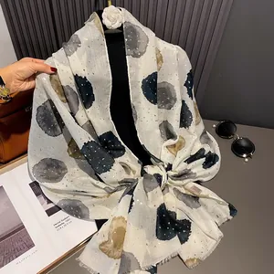 Beige cotton linen scarf with ink dots and gold sequins on a display stand