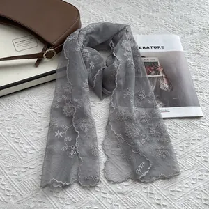Detail showing grey lace scarf with delicate floral embroidery and scalloped edges