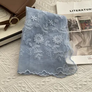 Close-up of light blue lace scarf with floral embroidery and French chic accessories