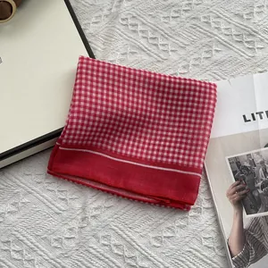 Klassieke rood-witte ruitjes katoenen vierkante sjaal netjes gevouwen op bureau