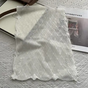 Détails de broderies florales sur châle en dentelle blanche avec bordure festonnée