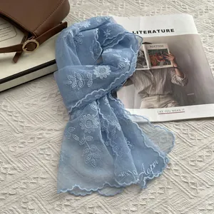 Detail of light blue lace scarf with white floral embroidery and wavy lace edges