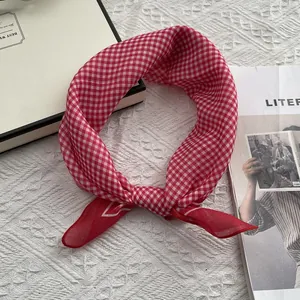 Detailopname van het rood-wit geruite katoenen sjaaltje op een witte tafelblad