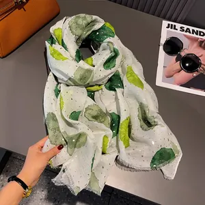 Detailed macro view of beige cotton linen scarf with green watercolor dots and gold foil