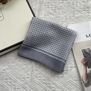 Detailopname van grijze gingham katoenen sjaal met gladde stiksels op zachte gebreide stof
