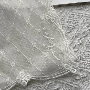 Détail de l'écharpe en dentelle blanche avec broderie rose et lettrage cursif élégant