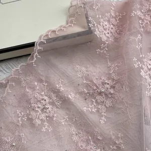 Detail of light pink floral lace with white pearls and shimmering sequins embroidery
