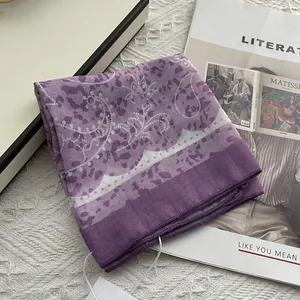Detail of purple paisley square scarf with delicate rolled edges and floral patterns