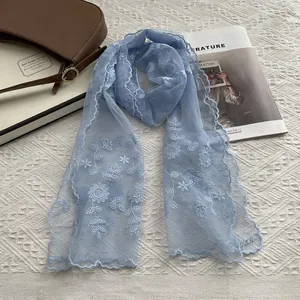 Detail of light blue lace scarf with sunflower embroidery and delicate wavy scalloped edges