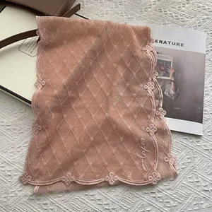 Détail du foulard en dentelle rose avec broderie en losange et bords fleuris en 3D