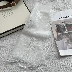 Detail of white lace scarf with floral embroidery and hand-sewn pearls for women