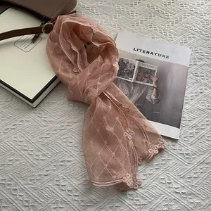 Détail d'une écharpe rose en dentelle brodée avec motifs floraux et bordures festonnées
