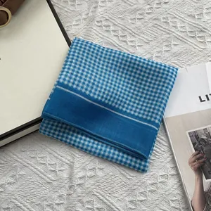 Detail van blauw-witte geruite katoenen sjaal met fijne textuur en zoomafwerking