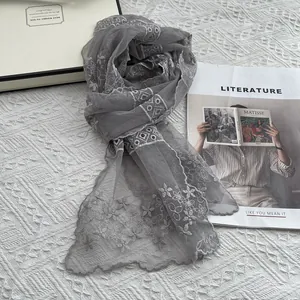 Detail eines grauen Spitzen-Schals mit Blumenstickerei und Wellenkante auf hellem Grund